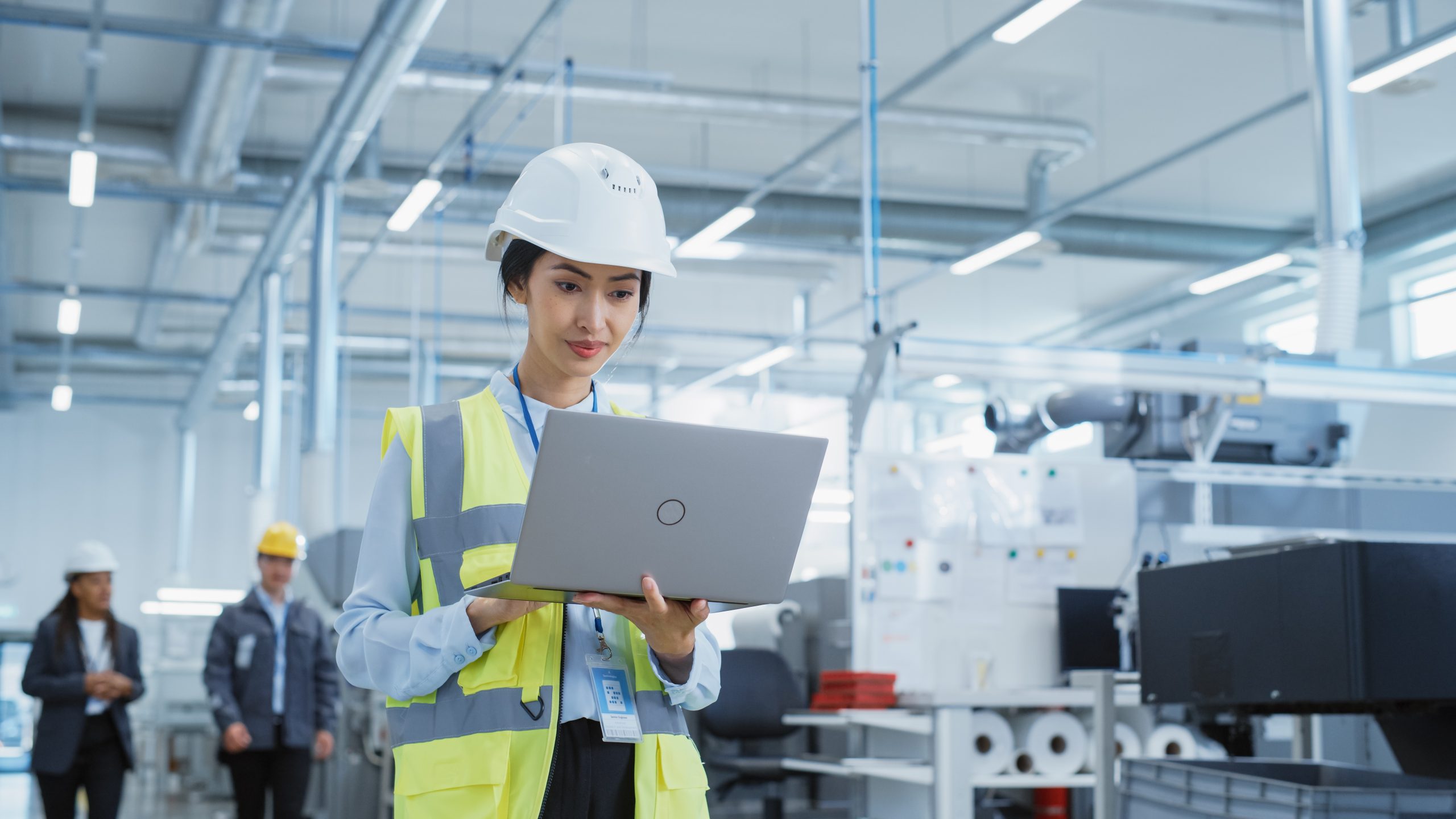 Technician holding a laptop, looking at production plans in a factory.