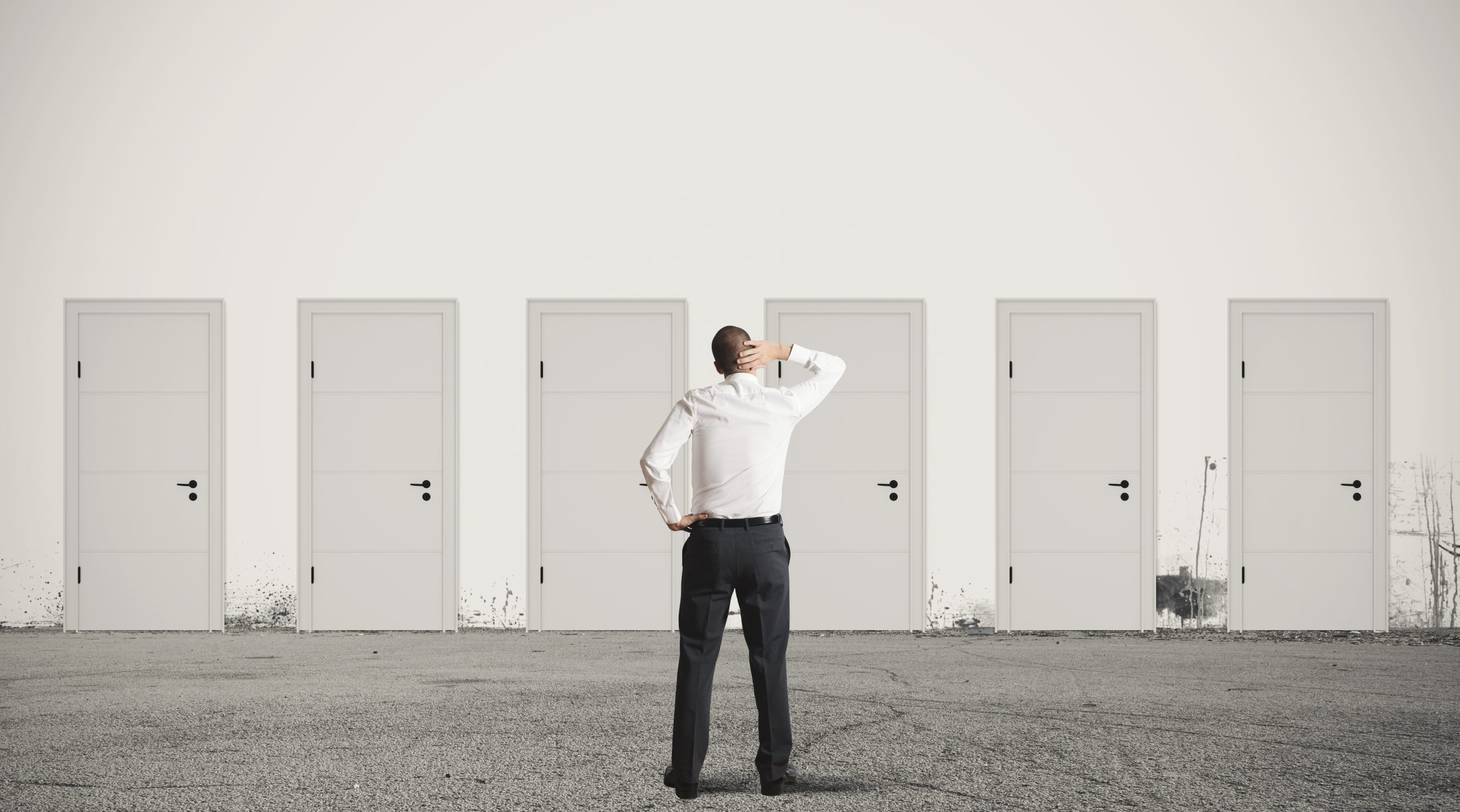 A person standing in front of 6 white doors seemingly struggling to make a decision