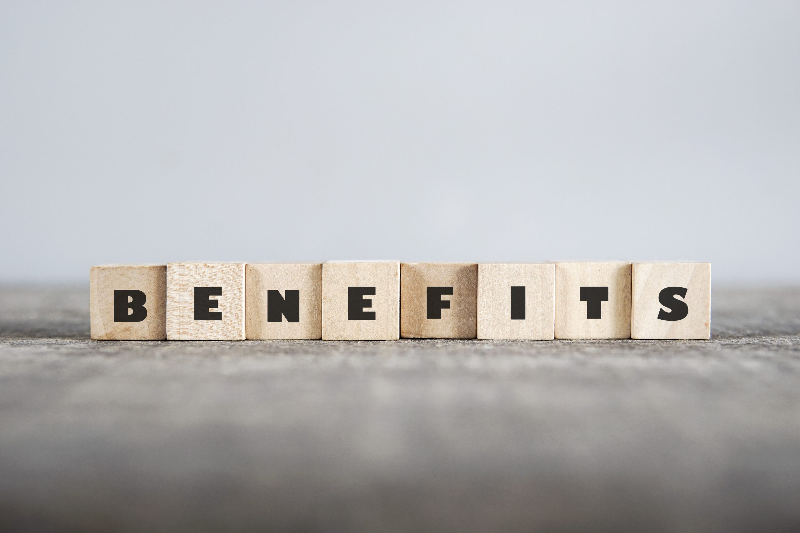 Wooden blocks with letters on them arranged on a table to spell out benefits