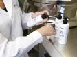 A person in a lab coat trying out hand lotion