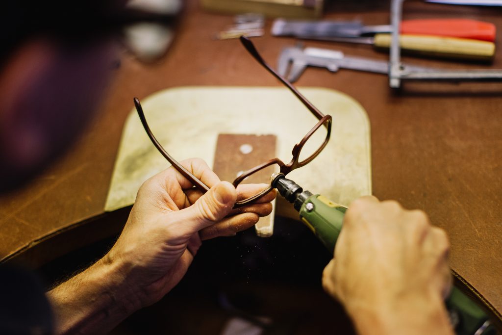 Glasses manufacturer using a grinding tool to make a new pair of wooden glasses. 