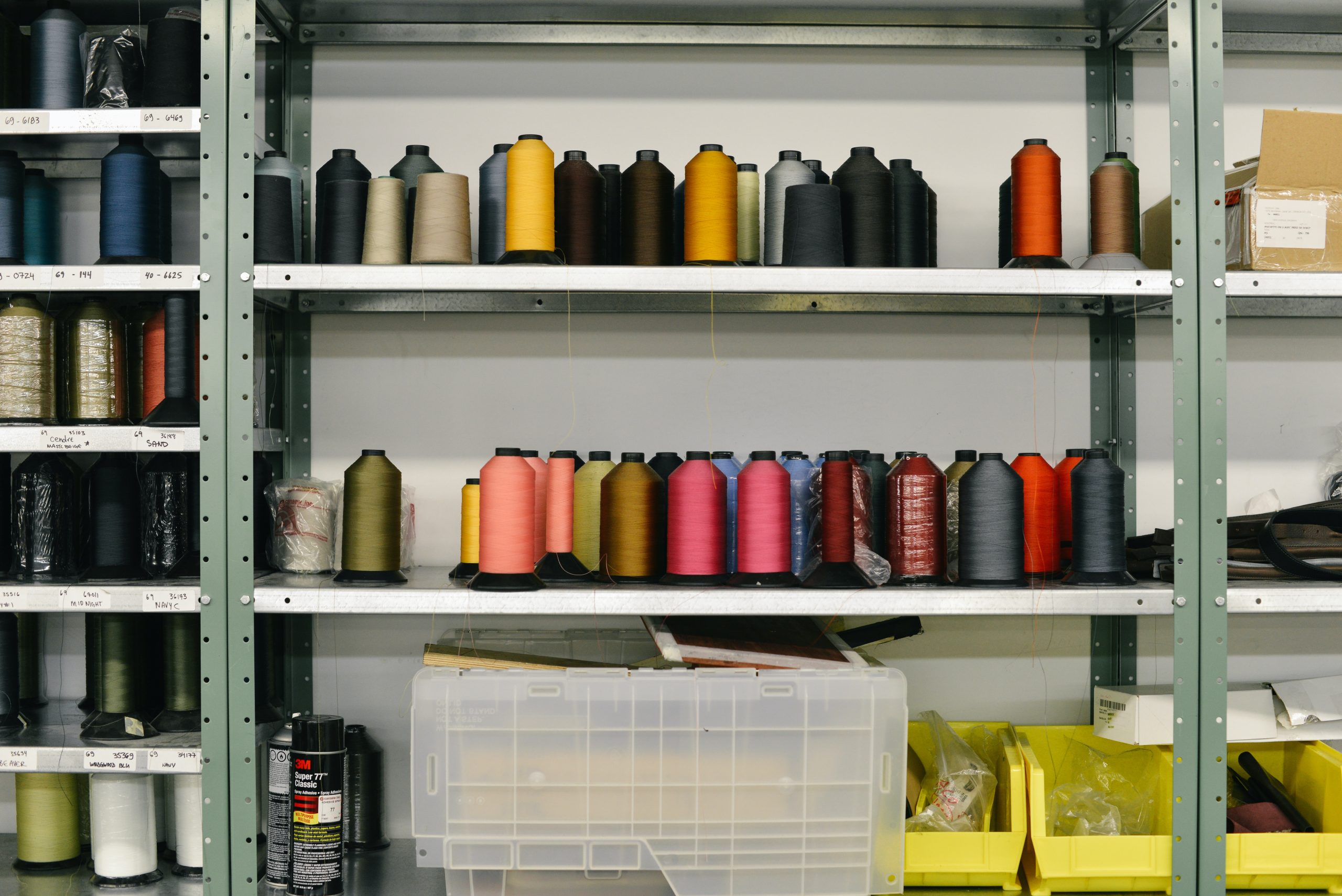 Several different colored yarn and thread on a shelf are ready to be used once production management is prepared.