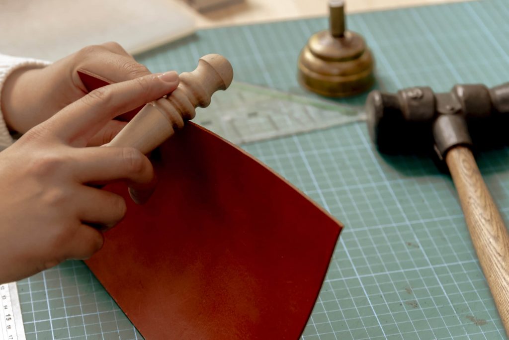 Close-up of a person sanding a sheet of leather