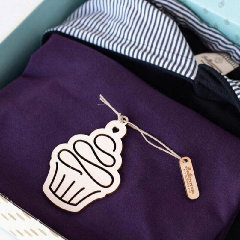 Clothes folded in a box with a cupcake-shaped label on them