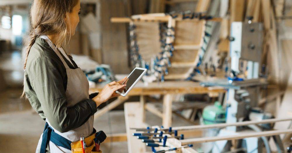 A worker holding a handheld device looking at production lines