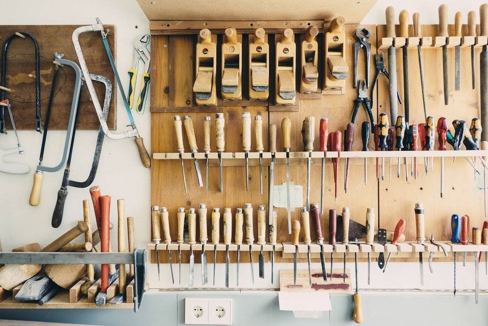 A workbench with a wall of tools behind the bench.