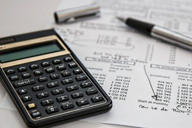Calculator and pen on a desk with documents to calculate MOQ