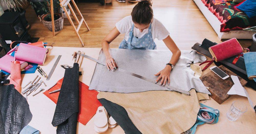 Worker at standing over a table measuring textile