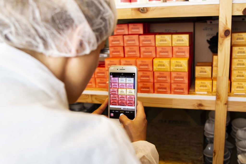 A cosmetic manufacturer using a smart device to scan the barcodes on their inventory