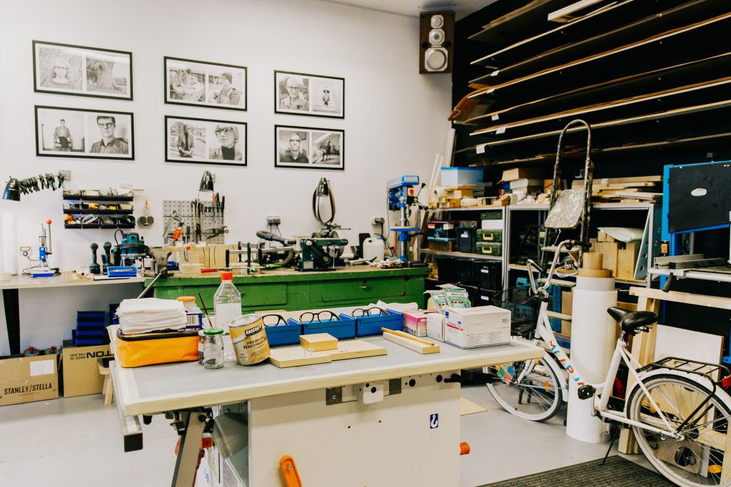 Image of a job shop manufacturing shop floor. It is filled with tools, products, materials, and different workstations. 