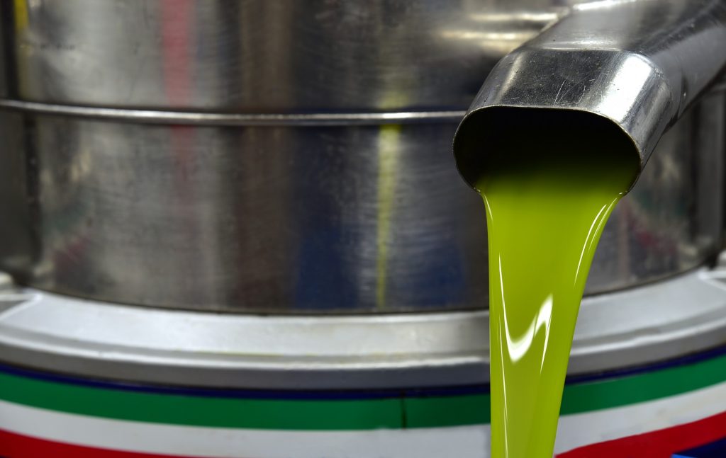 Extremely green thick olive oil pour out of a clean metallic machine. 