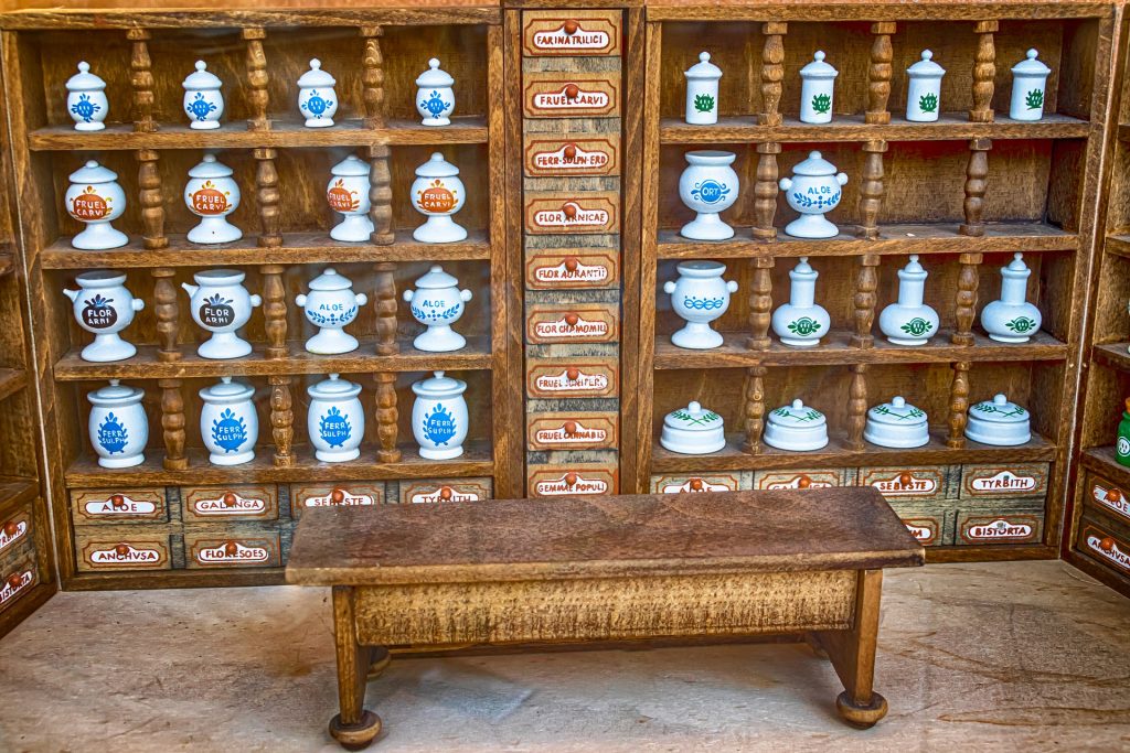Antique hand-carved shelving with white vases of various sizes filled with baking material. 