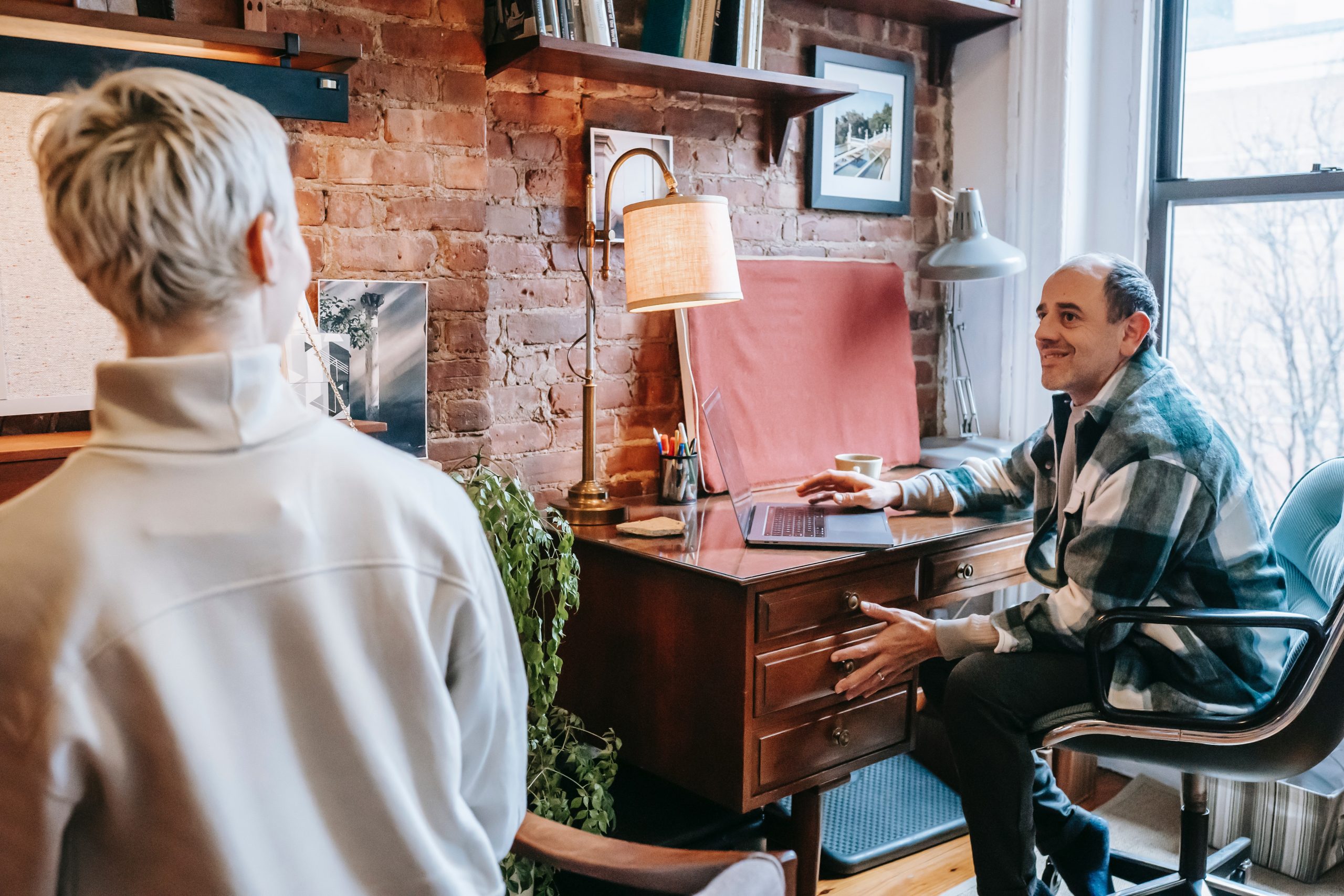 Two business owners in a rustic office discussing which is best: Shopify vs. Shopify Plus. 