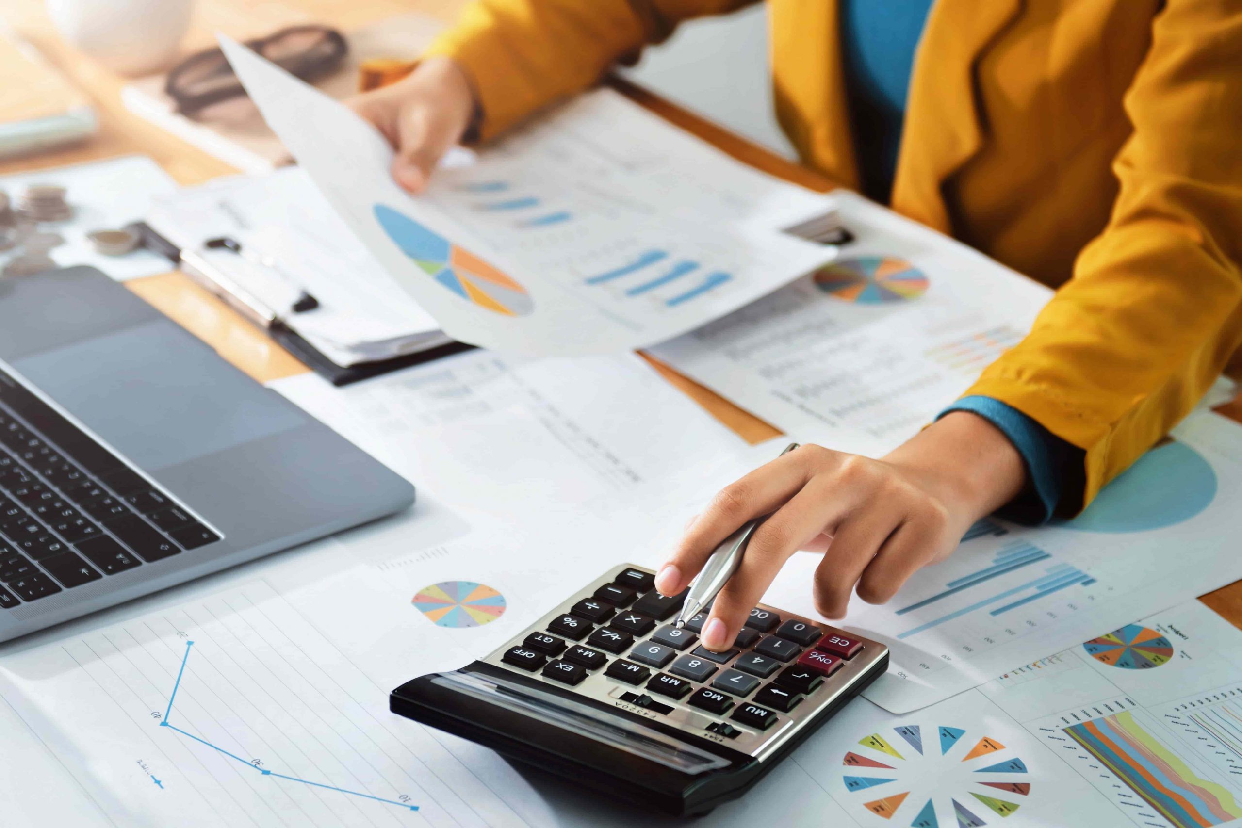 Accountant behind a desk punching in numbers on a calculator while looking at documents on the desk