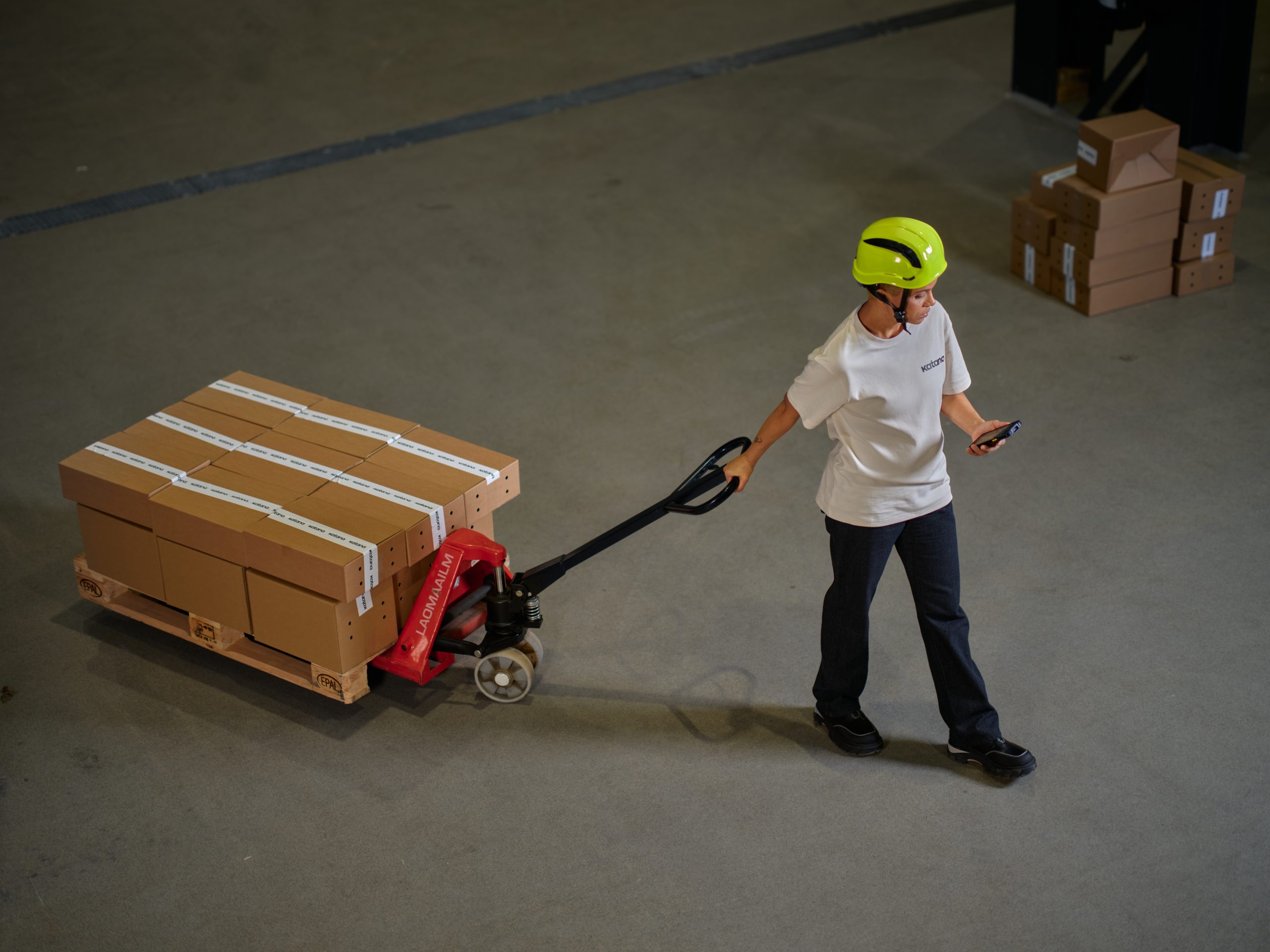 A warehouse worker moving boxes of inventory with a manual forklift