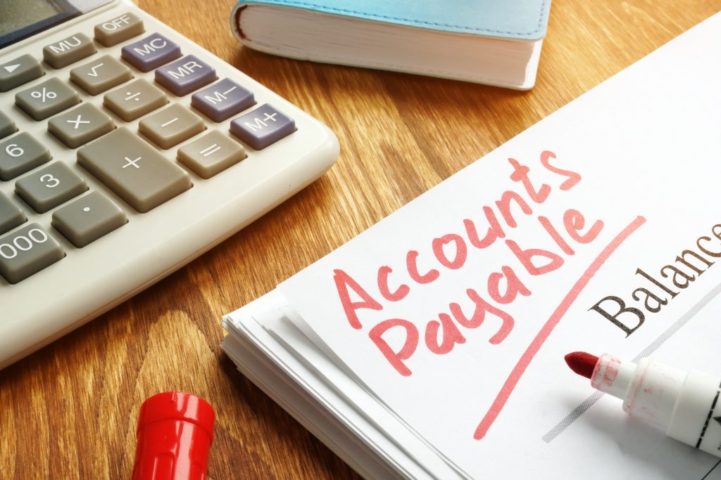 Accounts payable written on a paper with a red marker next to a calculator