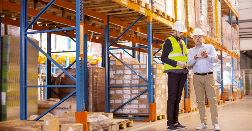 Two workers in warehouse looking at a notepad