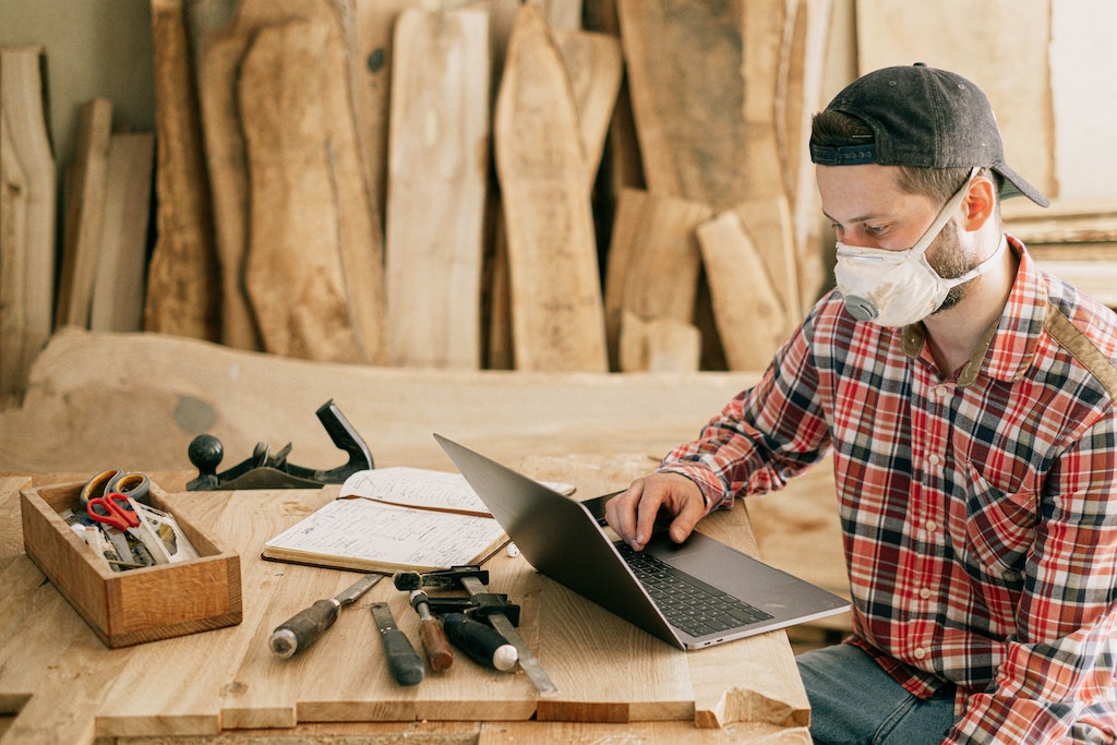 Man using laptop in wood workshop