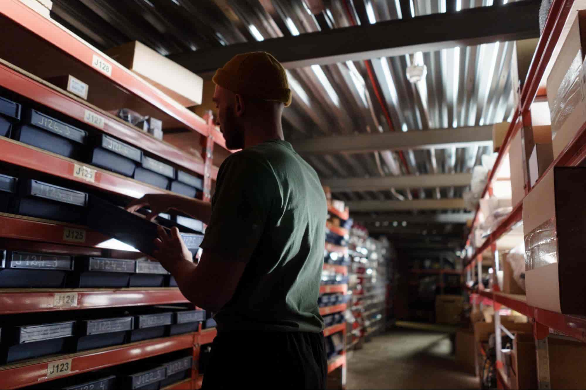 Man in a dark warehouse looking for raw materials.