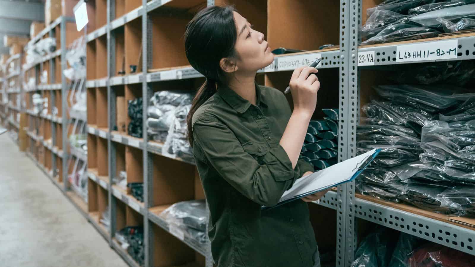 A female worker looking through inventory in a warehouse to calculate the business’ inventory days on hand.