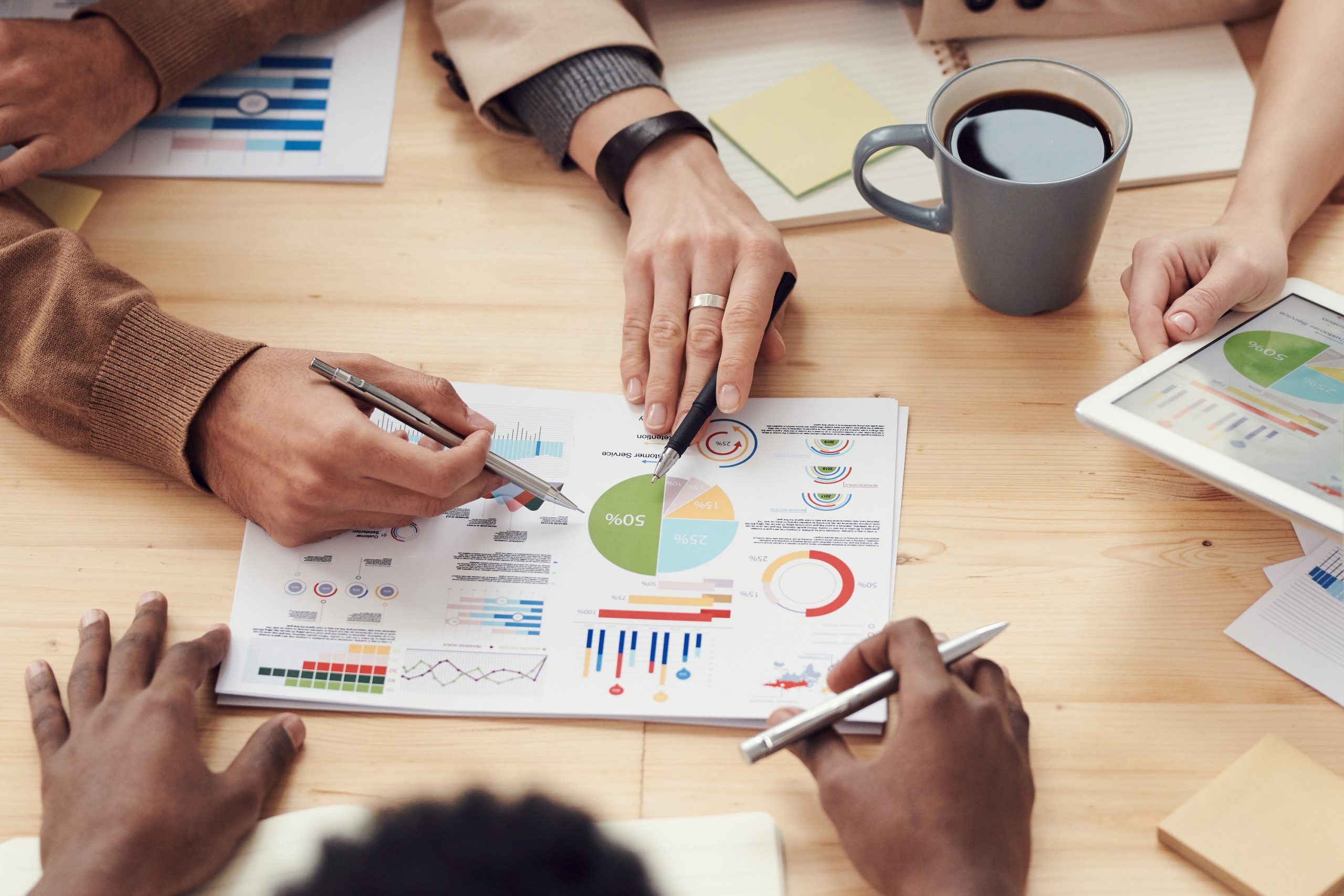 Hands pointing to graphs shown on a document laying on a desk