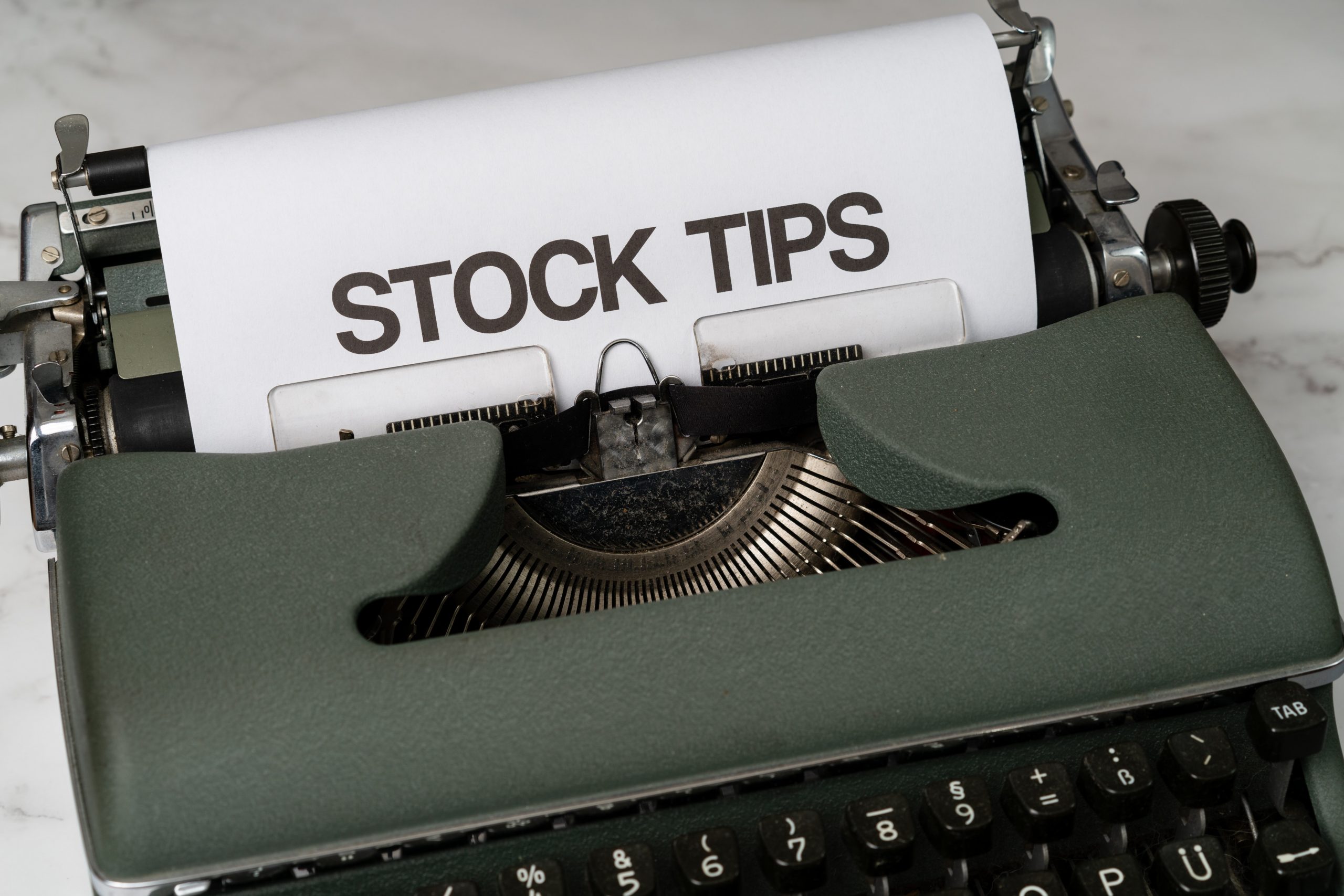 A paper sticking out of a typewriter with stock tips written on it 