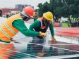 Two workers installing solar panels while wearing PPE manufacturing clothing and equipment.