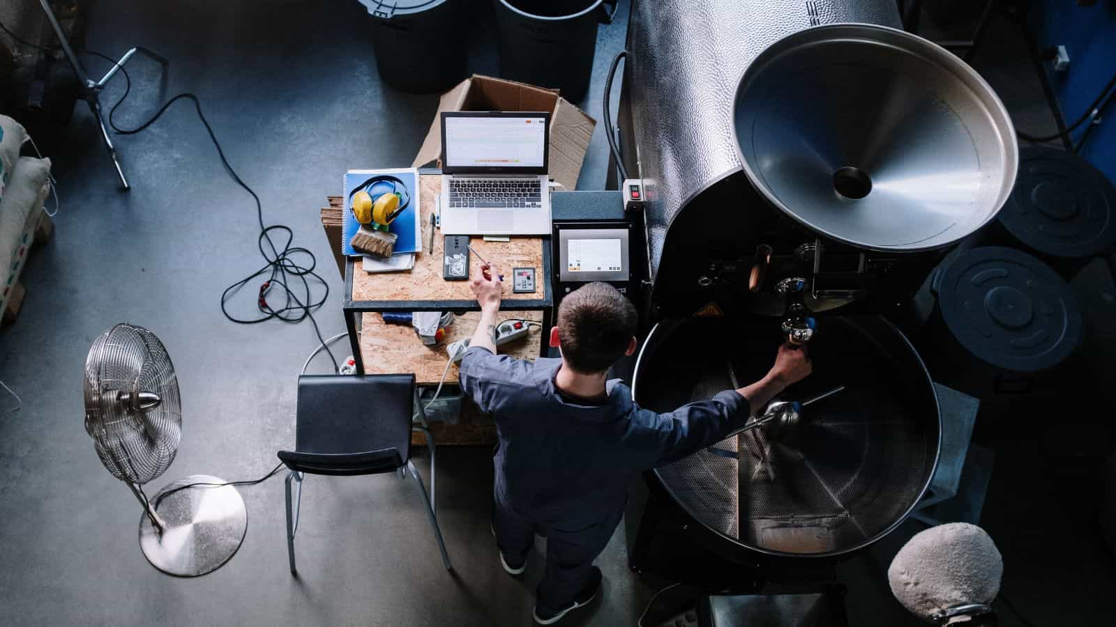 Worker using electronic measurement tools to ensure a coffee roaster is calibrated properly