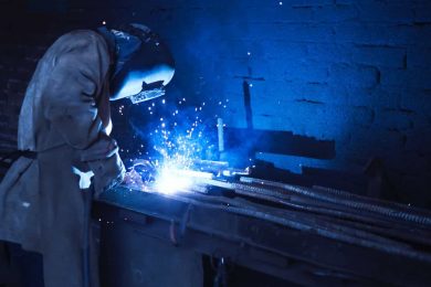 A worker welds two pieces of metal together in a workshop after choosing the best welding process after reading about the different types of welding techniques.