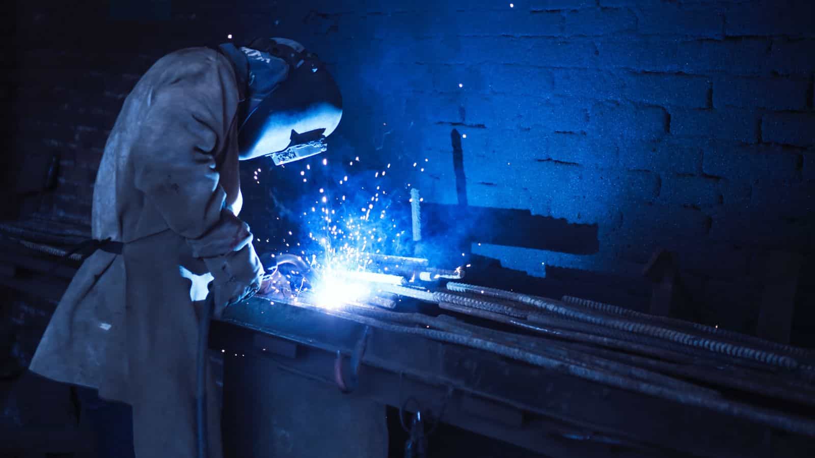 A worker welds two pieces of metal together in a workshop after choosing the best welding process after reading about the different types of welding techniques.