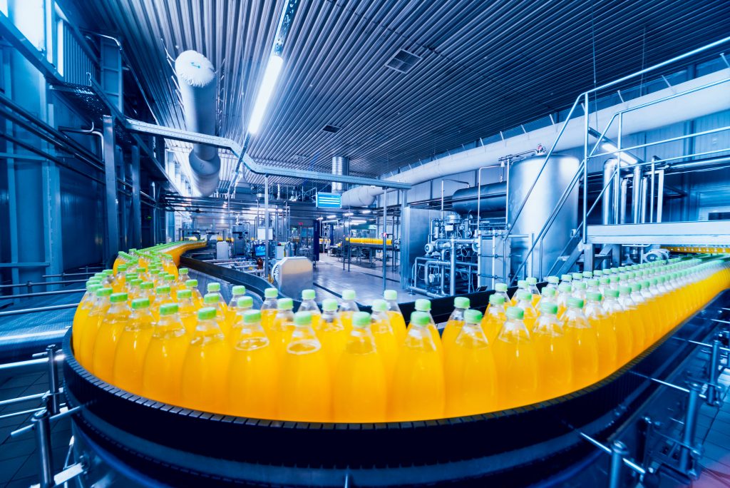Bottles containing yellow beverage on a converyor belt in a factory