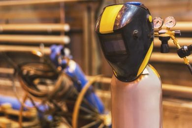 A welding mask hangs on equipment due to downtime in manufacturing.