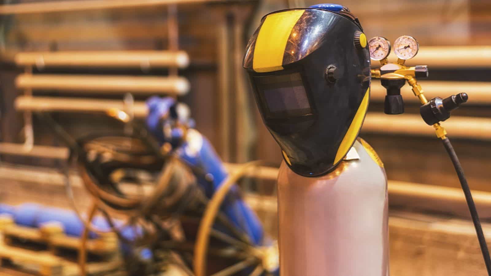 A welding mask hangs on equipment due to downtime in manufacturing.