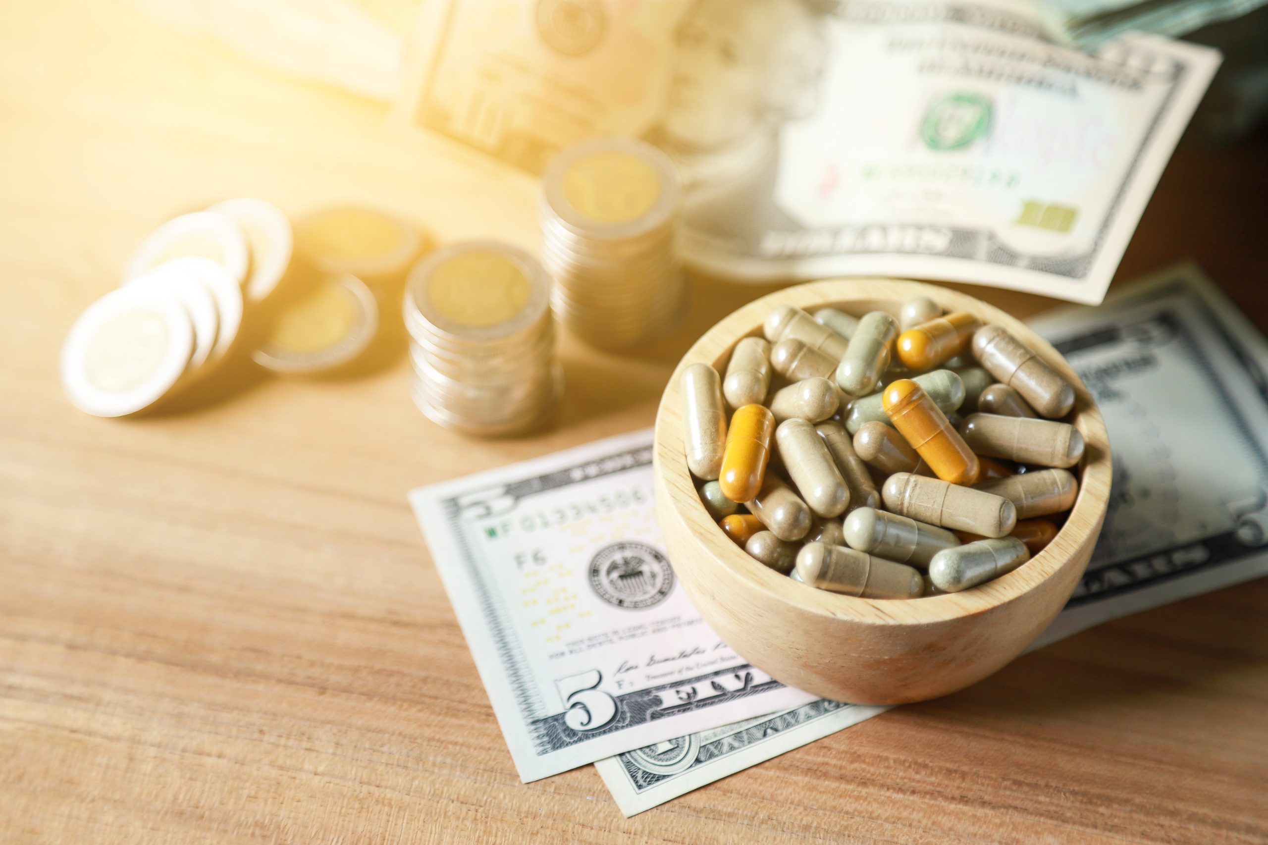 Supplement pills in a small bowl on a table next to coins and paper money