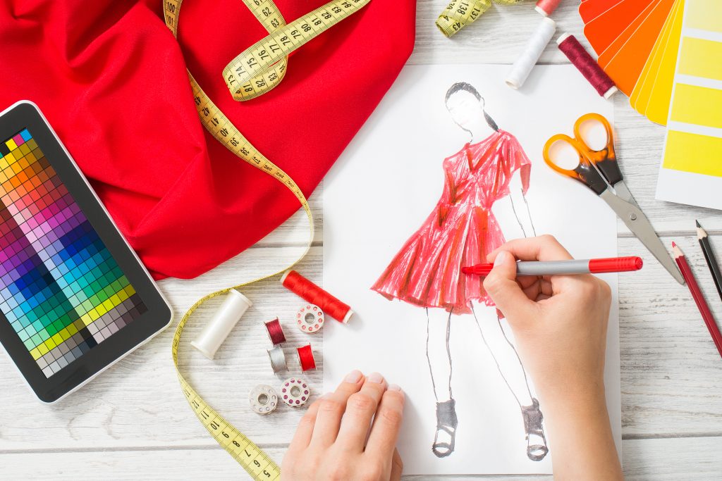 Designer drawing a red summer dress on paper