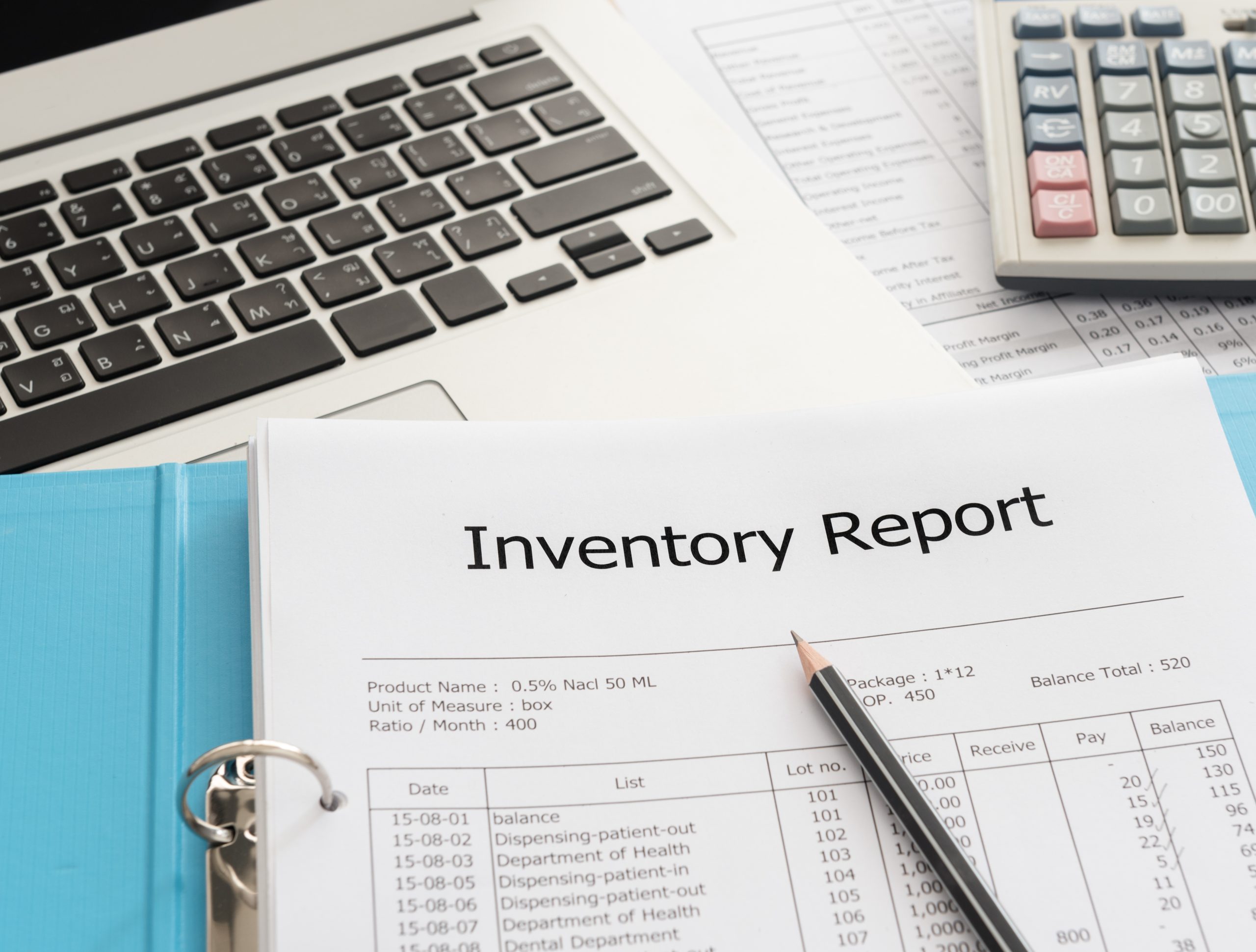 Inventory report on a desk next to a laptop and a calculator