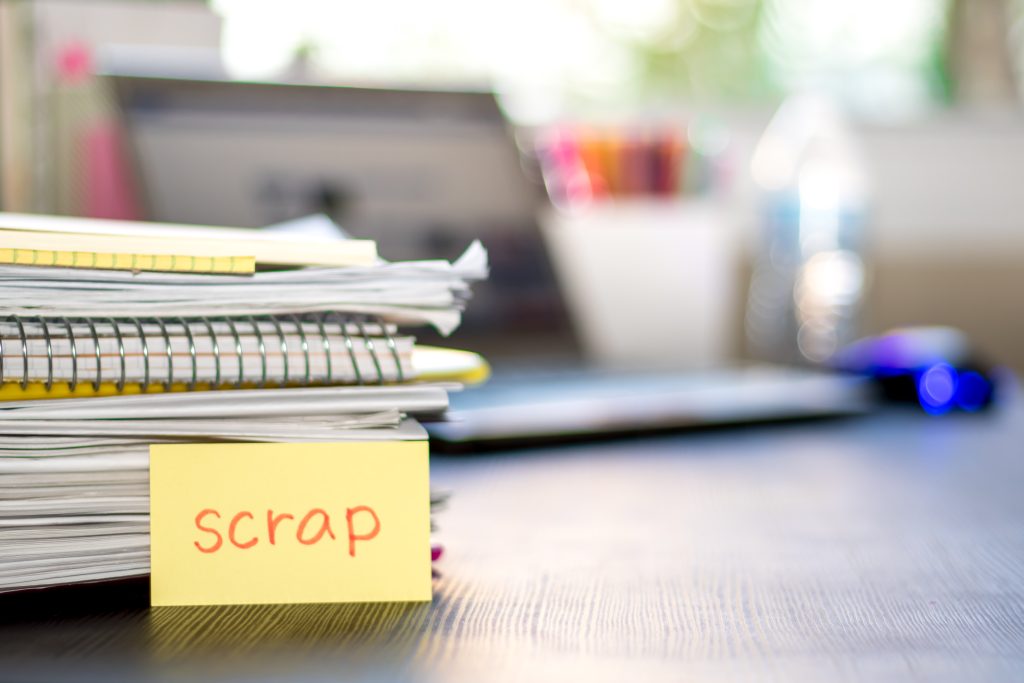A stack of notebooks on a desk, post-it note with "scrap" written on it