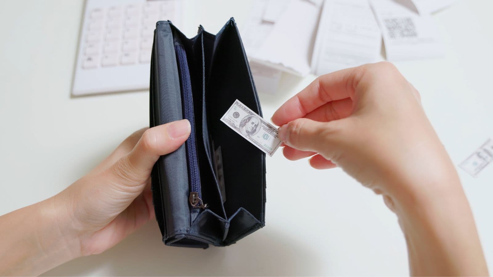 A small 100-dollar bill being pulled out of an empty wallet by an accountant.