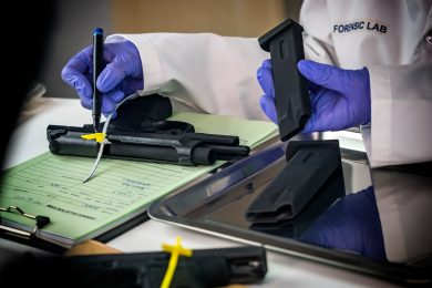 Forensic scientist marking down a weapon's serial number