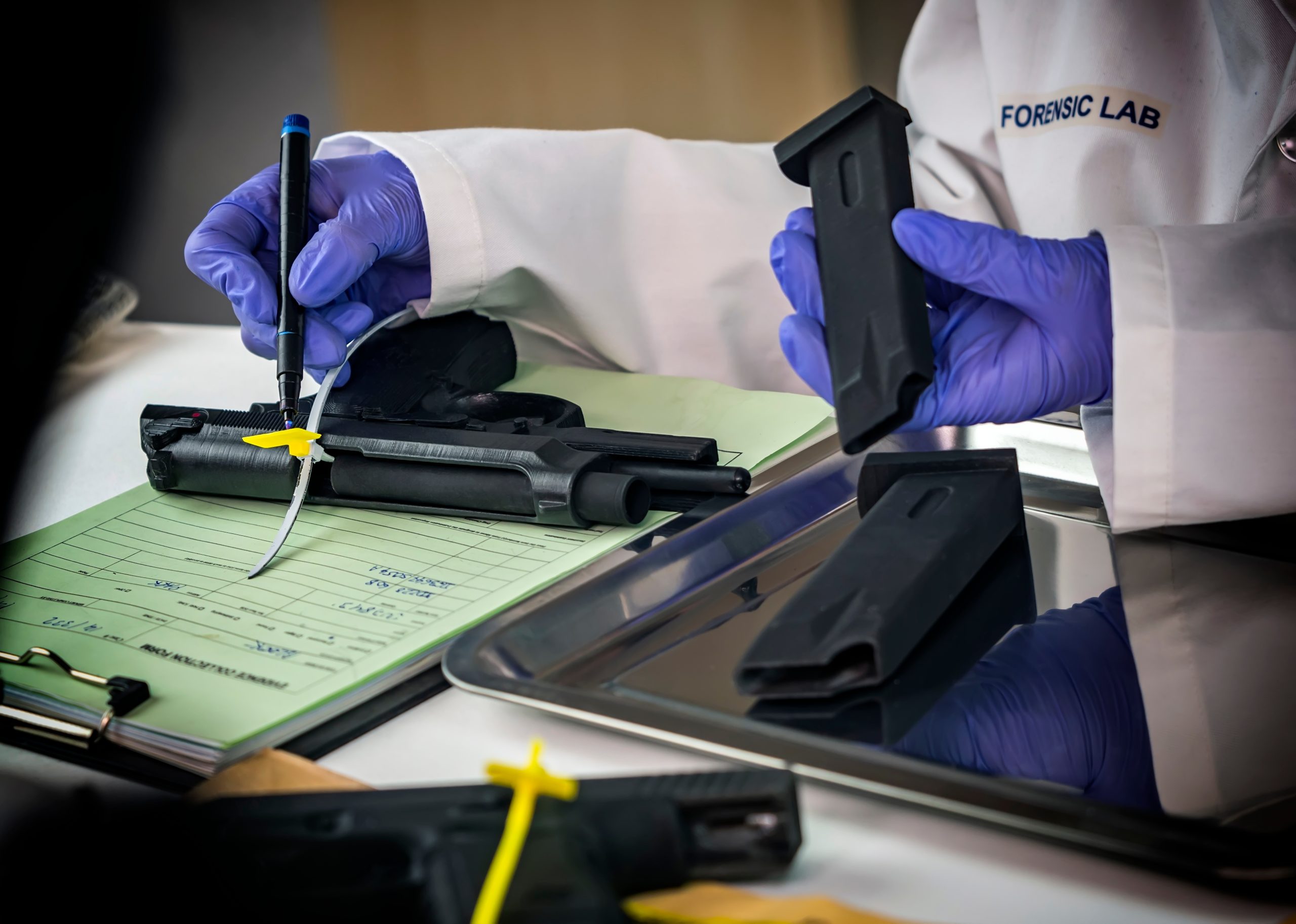 Forensic scientist marking down a weapon's serial number