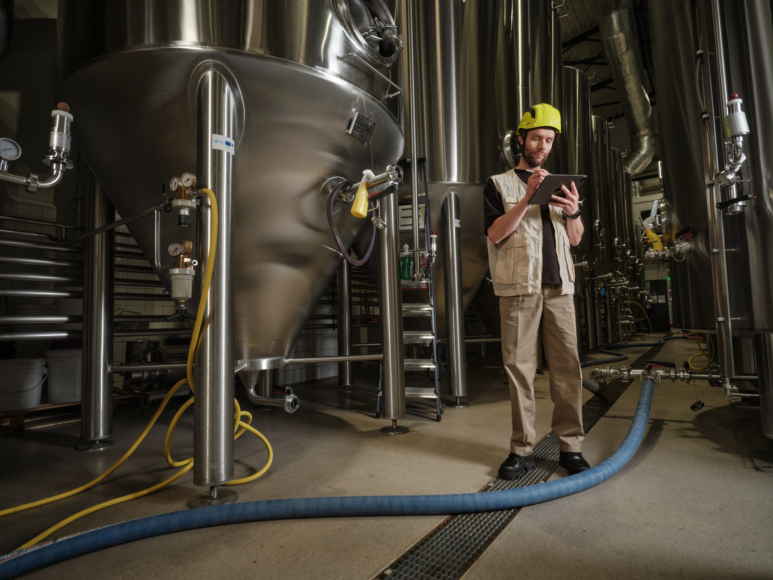 A worker standing in a brewery holding an ipad