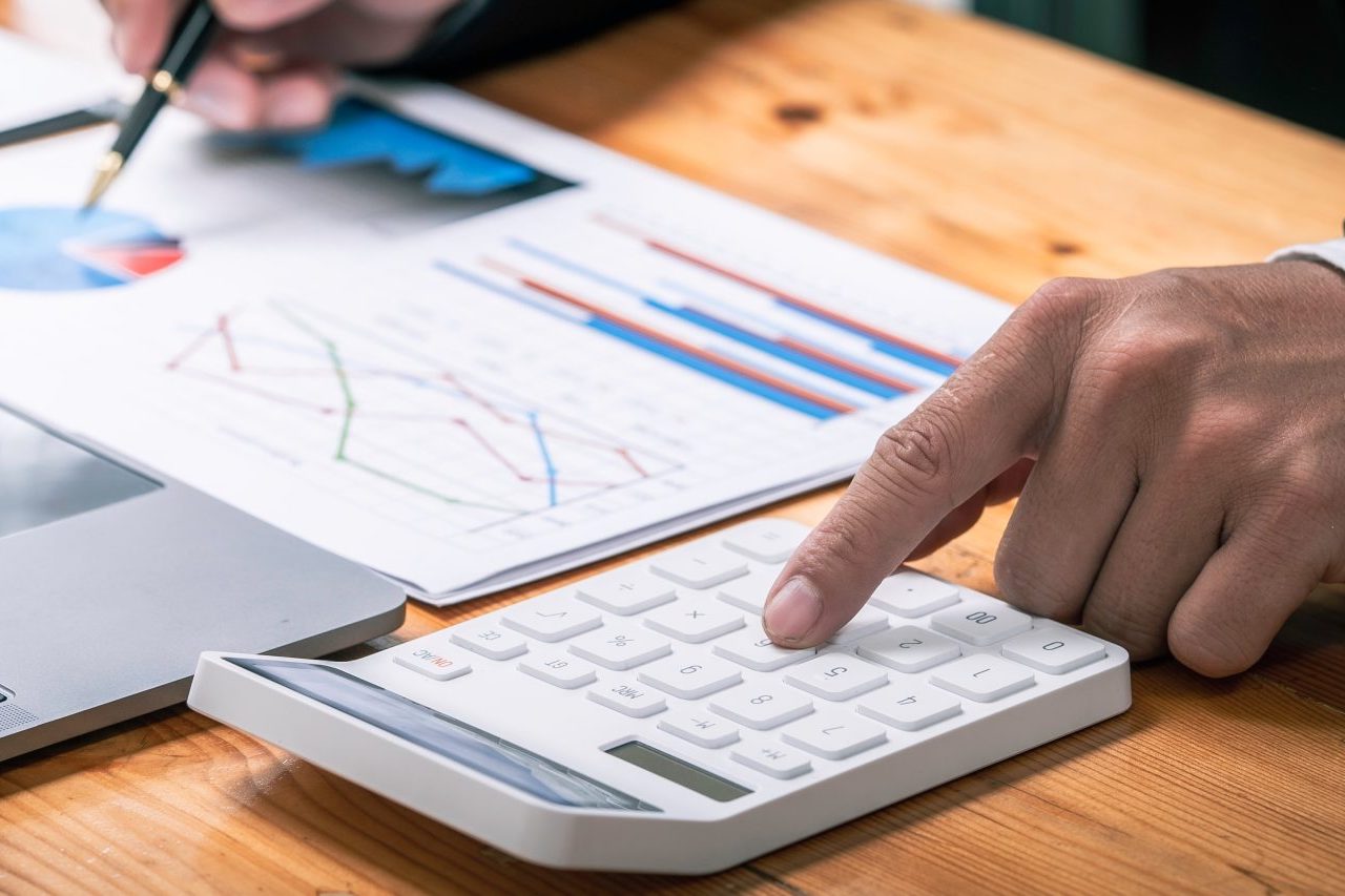 accountant working on a desk using calculator for calculating finance report in office, Annual tax calculation finances, and economy concept. Financial calculation concept, Accounting , Economic