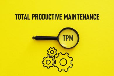 Total productive maintenance printed on a yellow background with gear icons and a magnifying glass