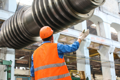 a man in hardhat conducting inspection of manufacturing equipment