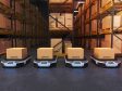 Four autonomous transportation robots carrying boxes in a warehouse