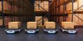 Four autonomous transportation robots carrying boxes in a warehouse