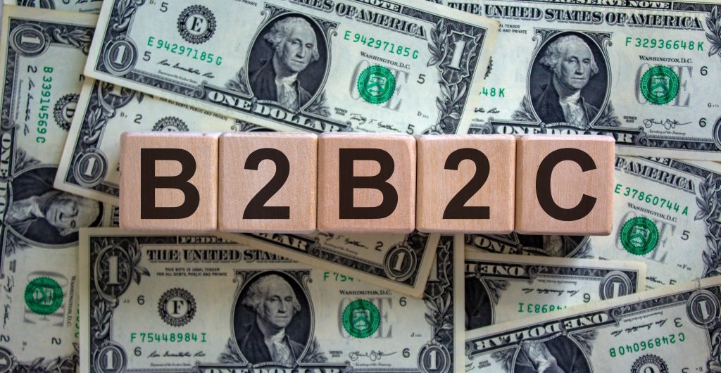 Wooden blocks with letters spelling out B2B2C on top of a pile of dollar bills