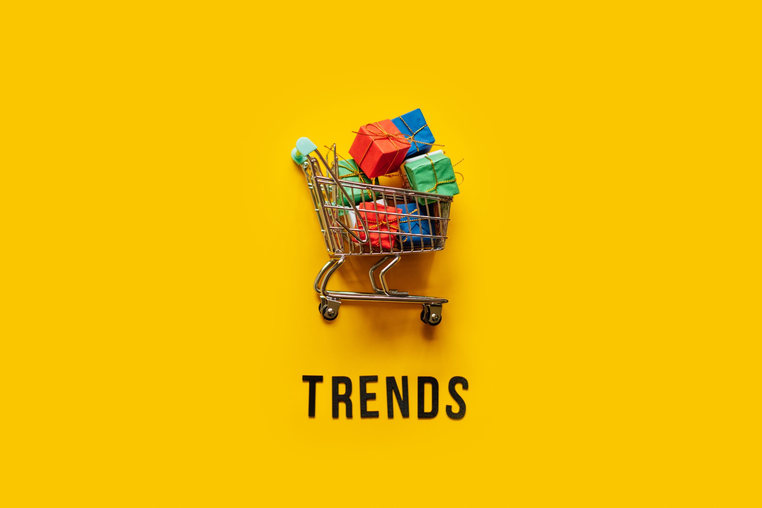 Shopping cart overfilled with boxes on a yellow background
